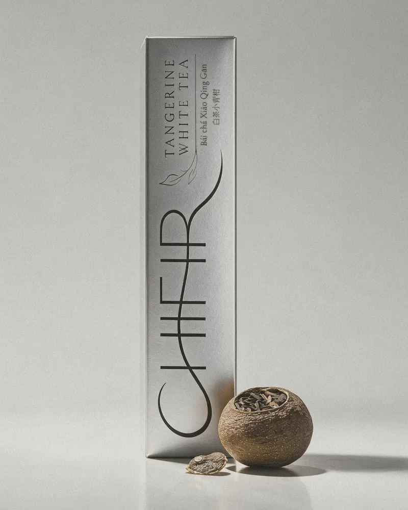 The silver carton standing upright on a pale foil ground, one whole dried tangerine and its cut stem cap beside it.