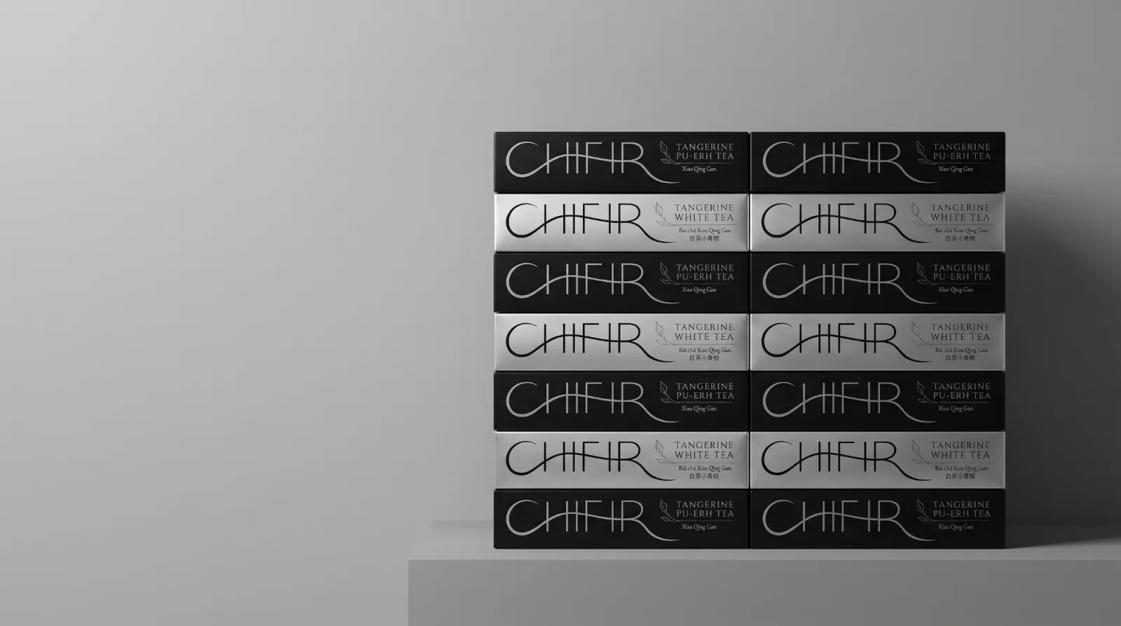 Fourteen CHIFIR boxes stacked in two columns on a grey plinth, black Tangerine Pu-erh boxes alternating with silver Tangerine White boxes.
